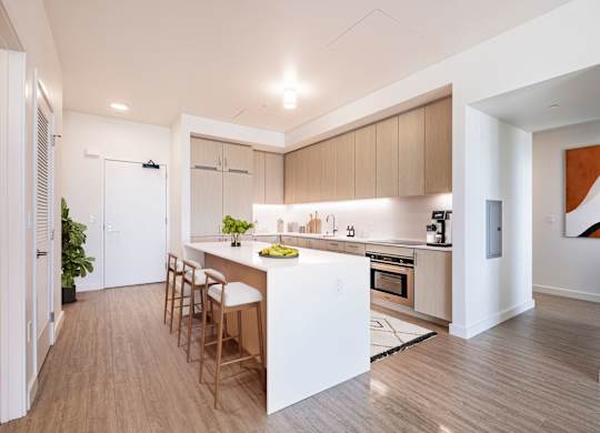 A modern kitchen with wooden floors and a white island.