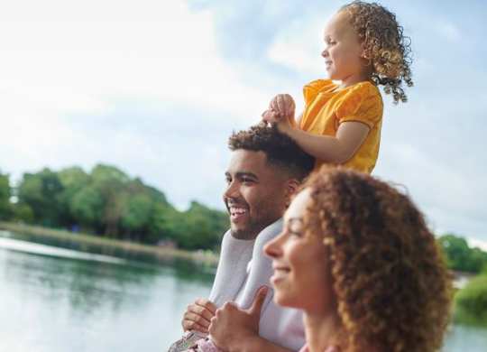 A family of three is enjoying a boat ride on a lake.