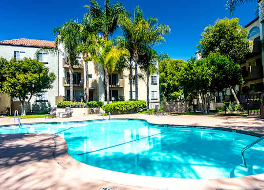 A swimming pool surrounded by palm trees and apartment buildings.at Norwalk Metropointe, Norwalk California  