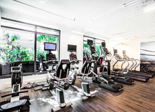 A gym with a row of treadmills and elliptical machines.at The Rise, San Francisco, 94103  