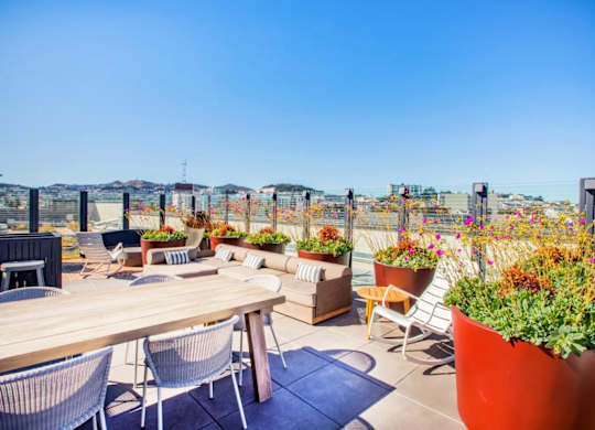 A patio with a table, chairs, and potted plants.at The Rise, California  