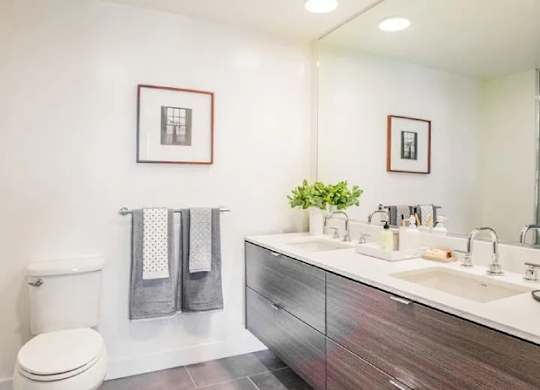 A bathroom with a toilet, sink, and mirror.at The Rise, California  