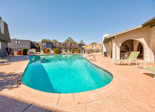 A small pool surrounded by a concrete floor and chairs.