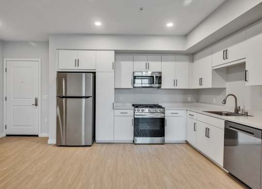 A modern kitchen with stainless steel appliances and wooden flooring.