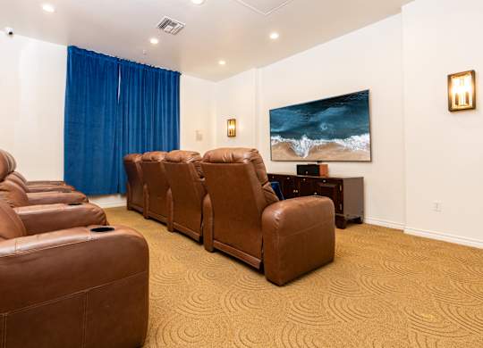 A room with brown leather chairs and a painting of a beach scene on the wall.
