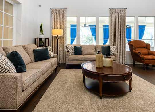 A living room with a beige couch, a round coffee table, and a chair.