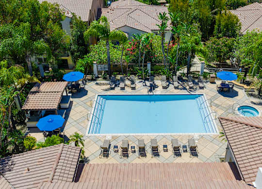 A large swimming pool surrounded by a tiled patio and lounge chairs.