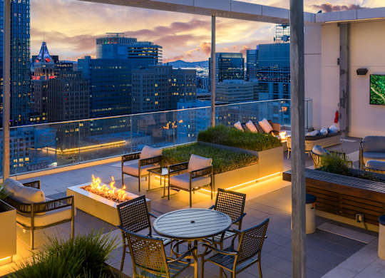 A rooftop patio with a table, chairs, and a TV.