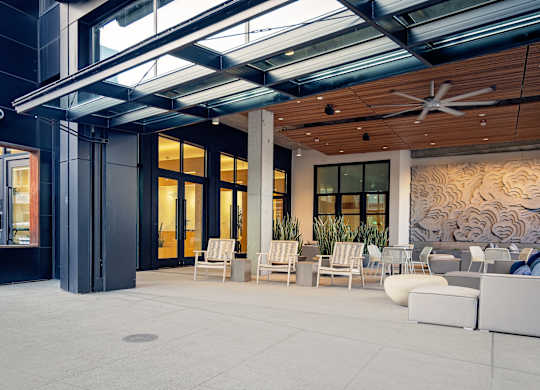 A modern outdoor seating area with white furniture and a wooden ceiling.