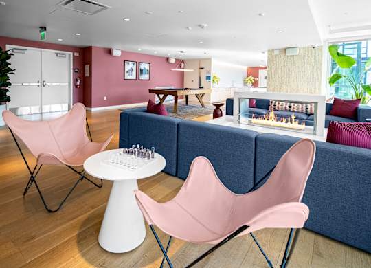A living room with a pink chair and a white table.