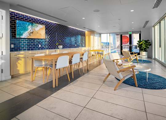A room with a long table and chairs with a blue tiled wall behind it.