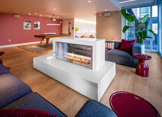 A modern living room with a white fireplace and blue couches.
