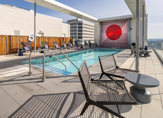 A pool with chairs and a table on a patio.