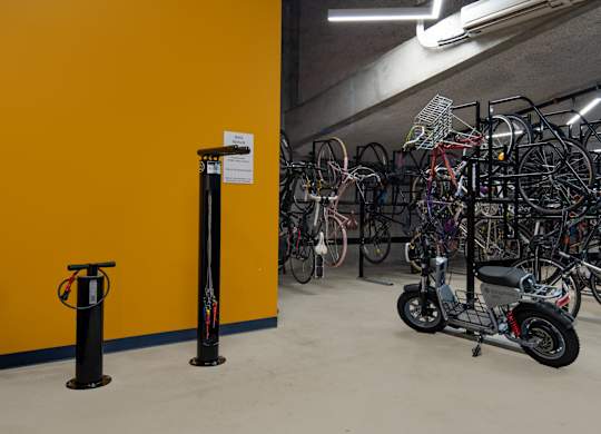 A yellow wall with a bike rack full of bicycles.