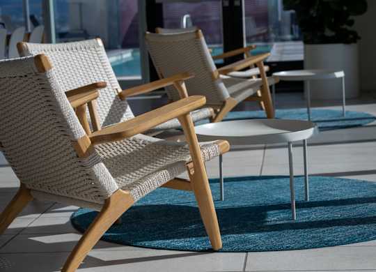 A row of wicker chairs are lined up on a patio.
