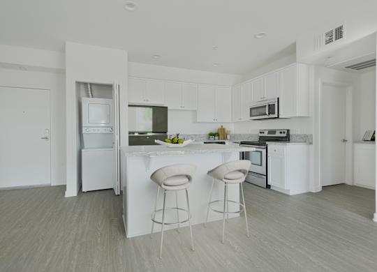 A white kitchen with a bar and stools.at 422 South Lake, California, 90057