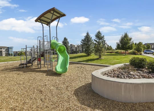a playground in a park with a large green slide at Parkside at Littleton Village, Colorado, 80122