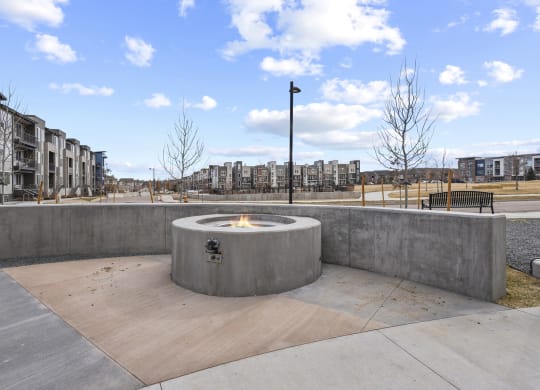 a fire pit in a park with buildings in the background at Parkside at Littleton Village, Littleton, CO