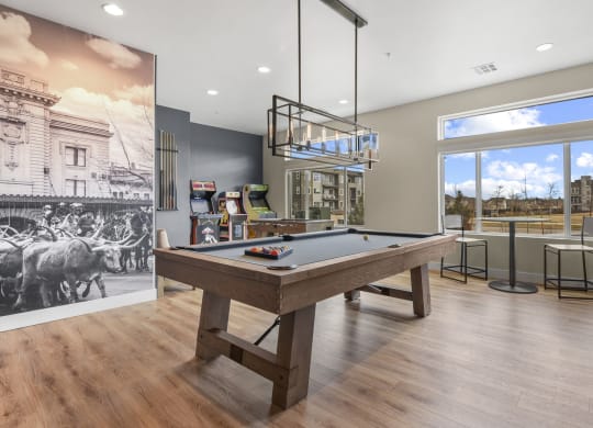a pool table in a clubhouse with a view of a bar and a large window at Parkside at Littleton Village, Littleton, Colorado