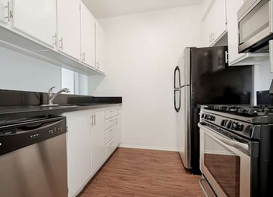 A kitchen with black appliances and white cabinets.at Plaza Lafayette, California, 90057