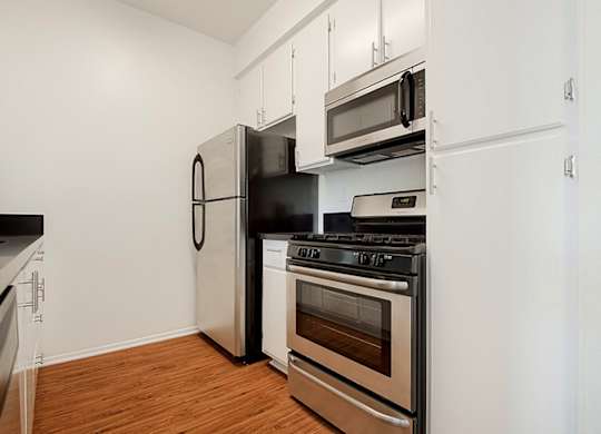 A kitchen with a black stove top oven and a black refrigerator.at Plaza Lafayette, Los Angeles  