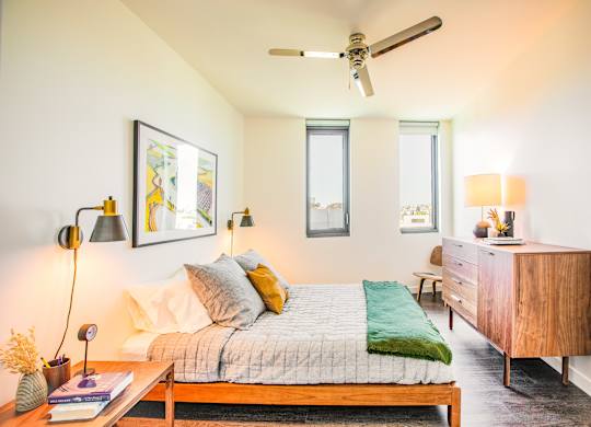 A bedroom with a bed, nightstand, and a ceiling fan.at The Rise, San Francisco California  