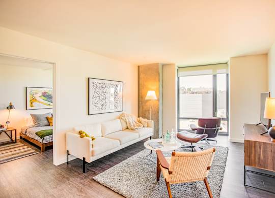 A well-lit, modern living room with a white sofa and a wooden chair.at The Rise, San Francisco, CA 94103  