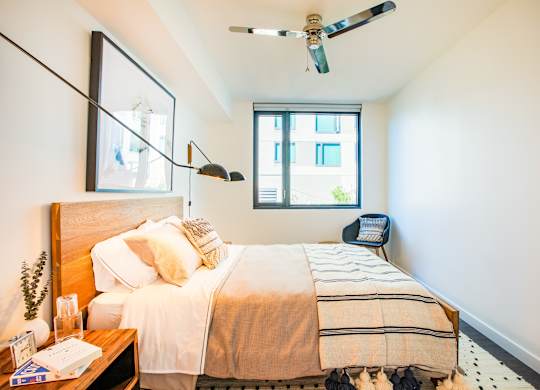A bedroom with a bed, a ceiling fan, and a window.at The Rise, California, 94103