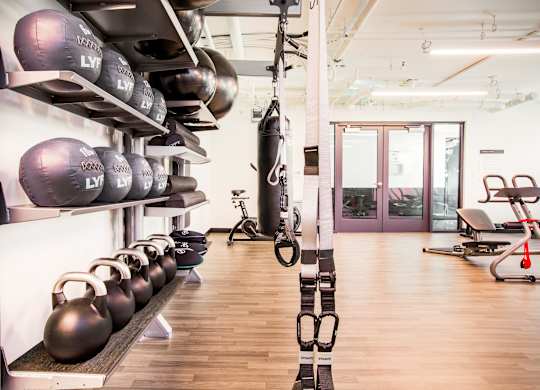 A gym with a row of kettlebells on the wall and a punching bag in the corner.at The Rise, San Francisco  