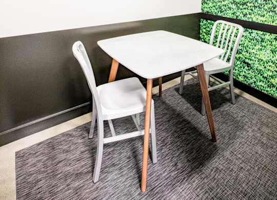 A white table with two chairs in front of a green plant wall.at The Rise, San Francisco  