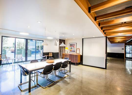 A modern dining room with a long table and chairs.at The Rise, California  