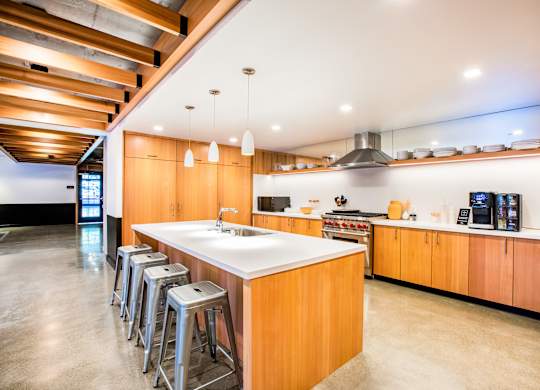 A modern kitchen with wooden cabinets and a large island.at The Rise, California, 94103