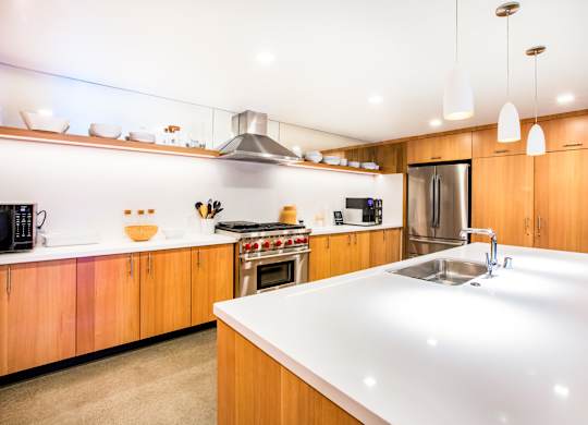 A modern kitchen with wooden cabinets and a white countertop.at The Rise, California  