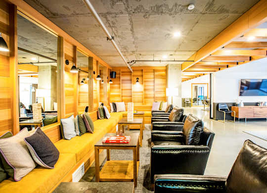 A long wooden bench with cushions is in the middle of a room with leather chairs.at The Rise, San Francisco  