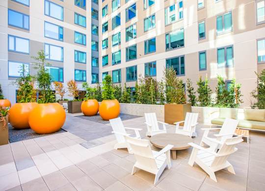 A patio with white chairs and a table with orange chairs.at The Rise, California  