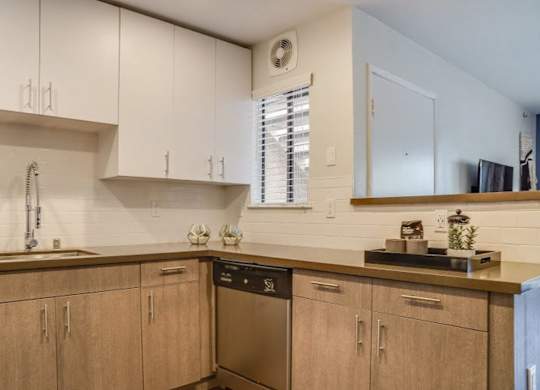 A kitchen with wooden cabinets and a stainless steel dishwasher.at Solterra At Civic Center, California, 90650-8308