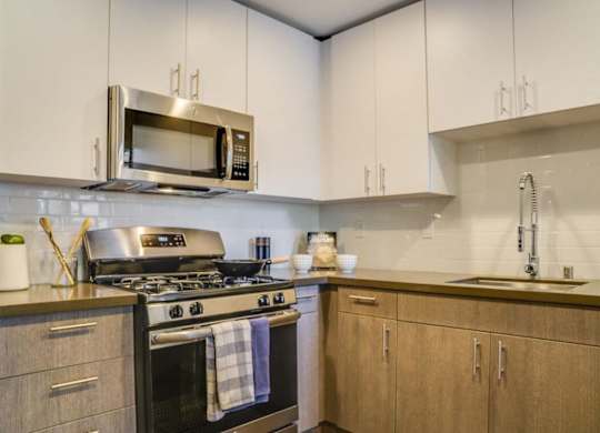 A modern kitchen with a stove, microwave, and cabinets.at Solterra At Civic Center, Norwalk  