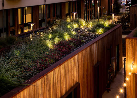 A modern apartment building with balconies and a green roof.