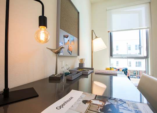 A modern desk with a lamp, a light bulb, and a few other items on it.
