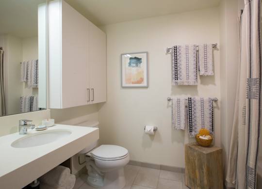 A bathroom with a toilet, sink, and a picture on the wall.