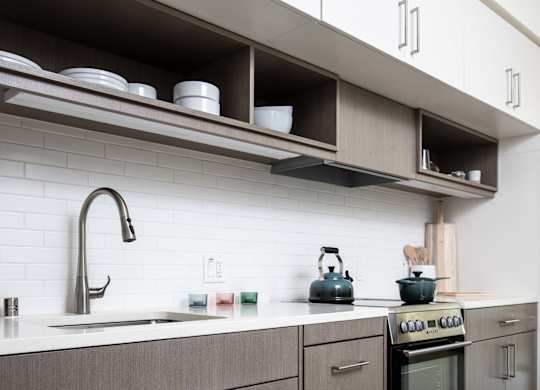 A modern kitchen with a stove, sink, and cabinets.