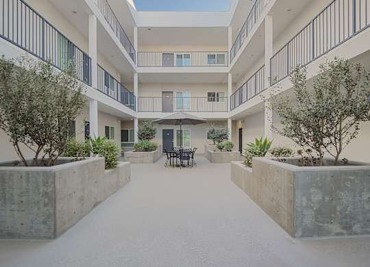 A courtyard with a concrete floor and a white building with balconies.