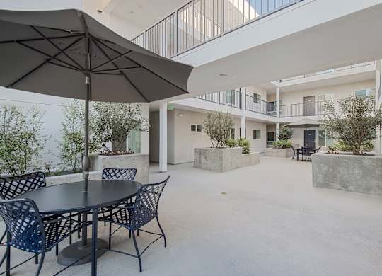 A patio with a table and chairs under an umbrella.
