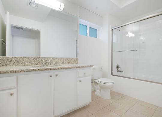 A white bathroom with a toilet, sink, and shower.