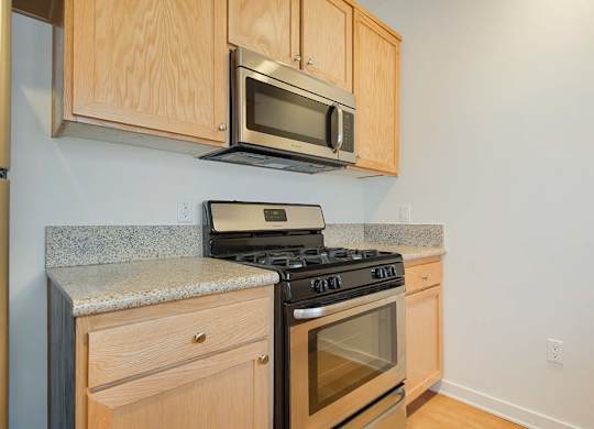 A kitchen with a stove, microwave, and cabinets.