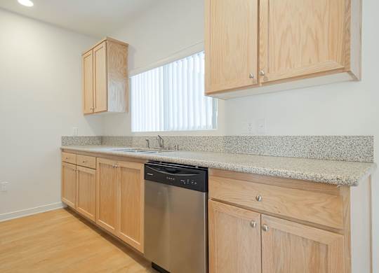 A kitchen with wooden cabinets and a granite countertop.