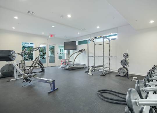 A gym with a variety of equipment including treadmills, weights, and exercise machines.