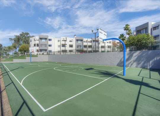 a green basketball court with buildings in the background at Vaseo Apartments, Phoenix, 85022