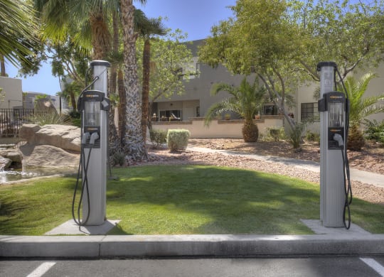 two gas pumps in a parking lot in front of a house at Vaseo Apartments, Phoenix, 85022