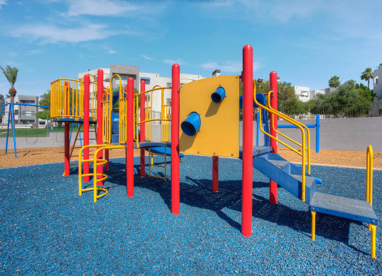 a playground with a yellow and red structure in a park at Vaseo Apartments, Phoenix, AZ